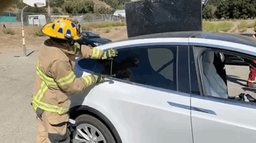 Auto extrication EV specialist breaking the window of a Tesla Model X